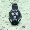 Men's chronograph watch with black strap on textured green surface, luxury moon-inspired design