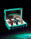 Three luxury men's wristwatches in a display case with space-themed background.