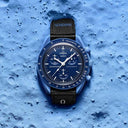 Blue men's chronograph wristwatch with black strap on textured blue lunar surface