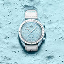 Light blue chronograph men's wristwatch with white strap on textured blue lunar surface